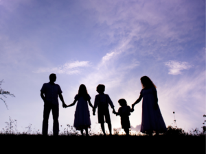 Family shadow holding hands against a cloudy yet bright sky.